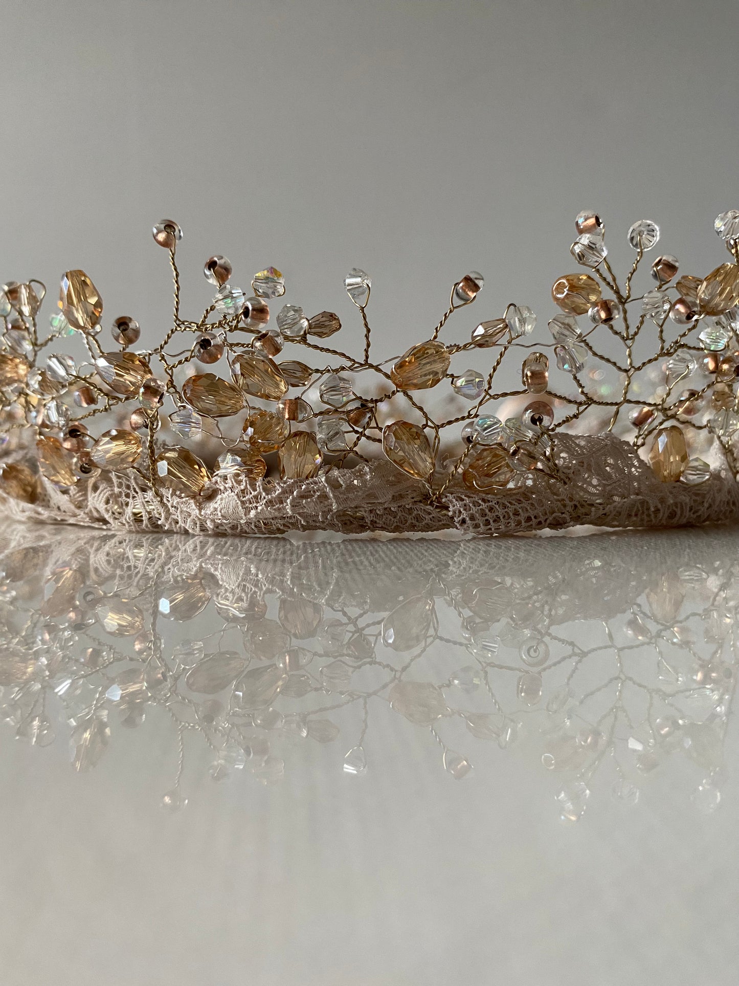 Stikla pērļu kronis baltos, bēšos un caurspīdīgos toņos ar mežģīnes apdares pamatni bēšā krāsā, sasienams