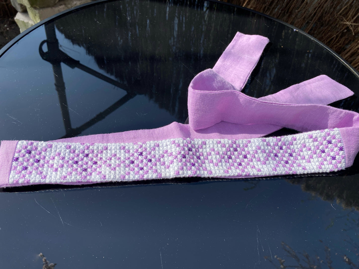 Krustdūrienā izšūta josta gaiši violetos toņos uz balta fona