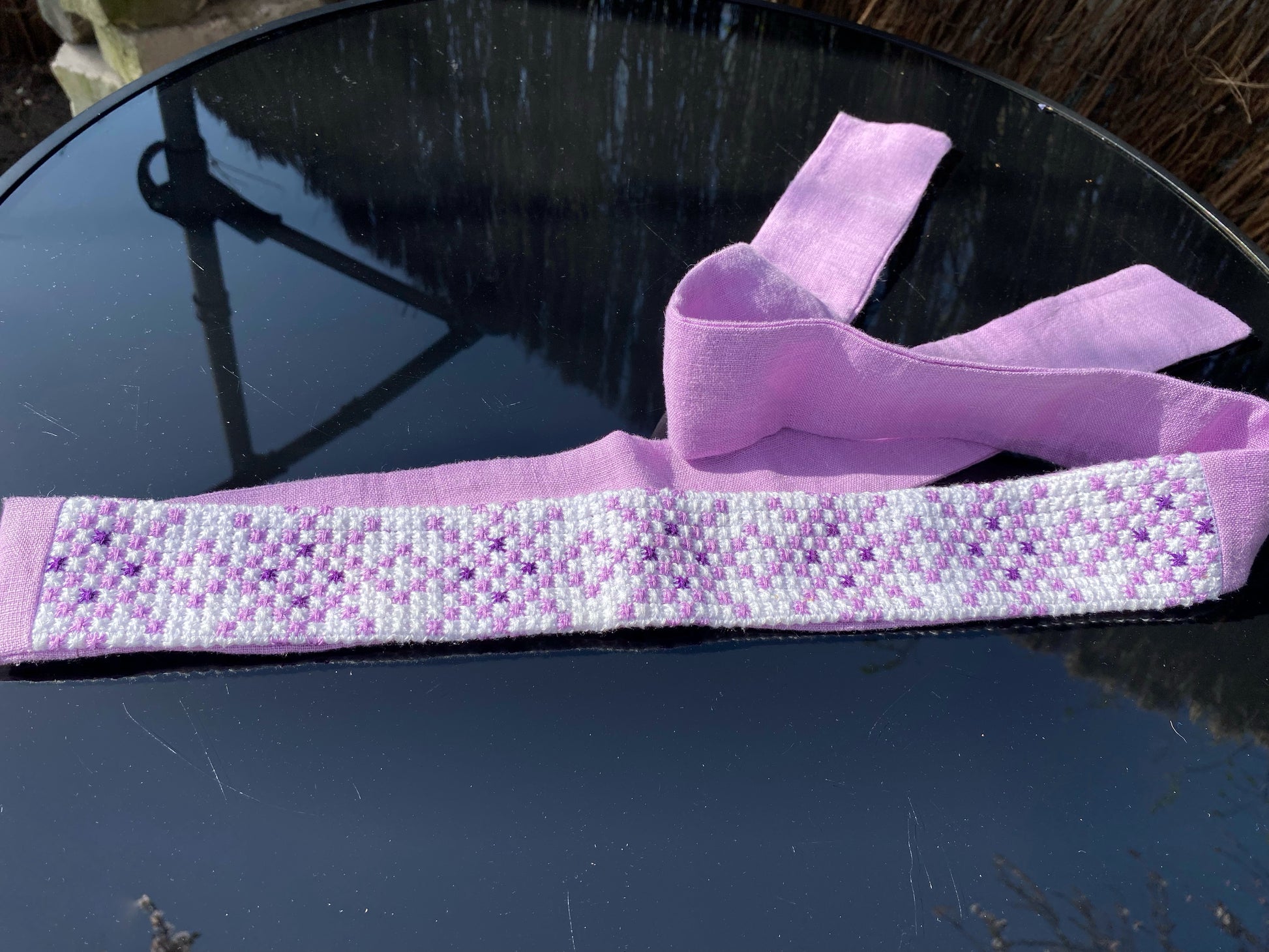 Krustdūrienā izšūta josta gaiši violetos toņos uz balta fona