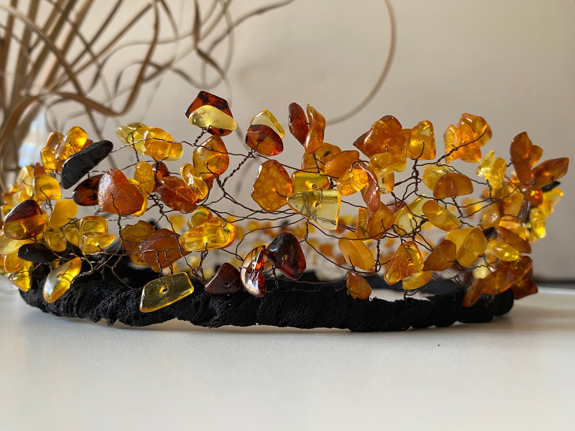 Stikla pērļu kronis no kopala (priežu sveķu) pērlēm. Dažādi oranži-brūnie, kā arī tumši brūnie toņi uz melnas pamatnes, sasienams