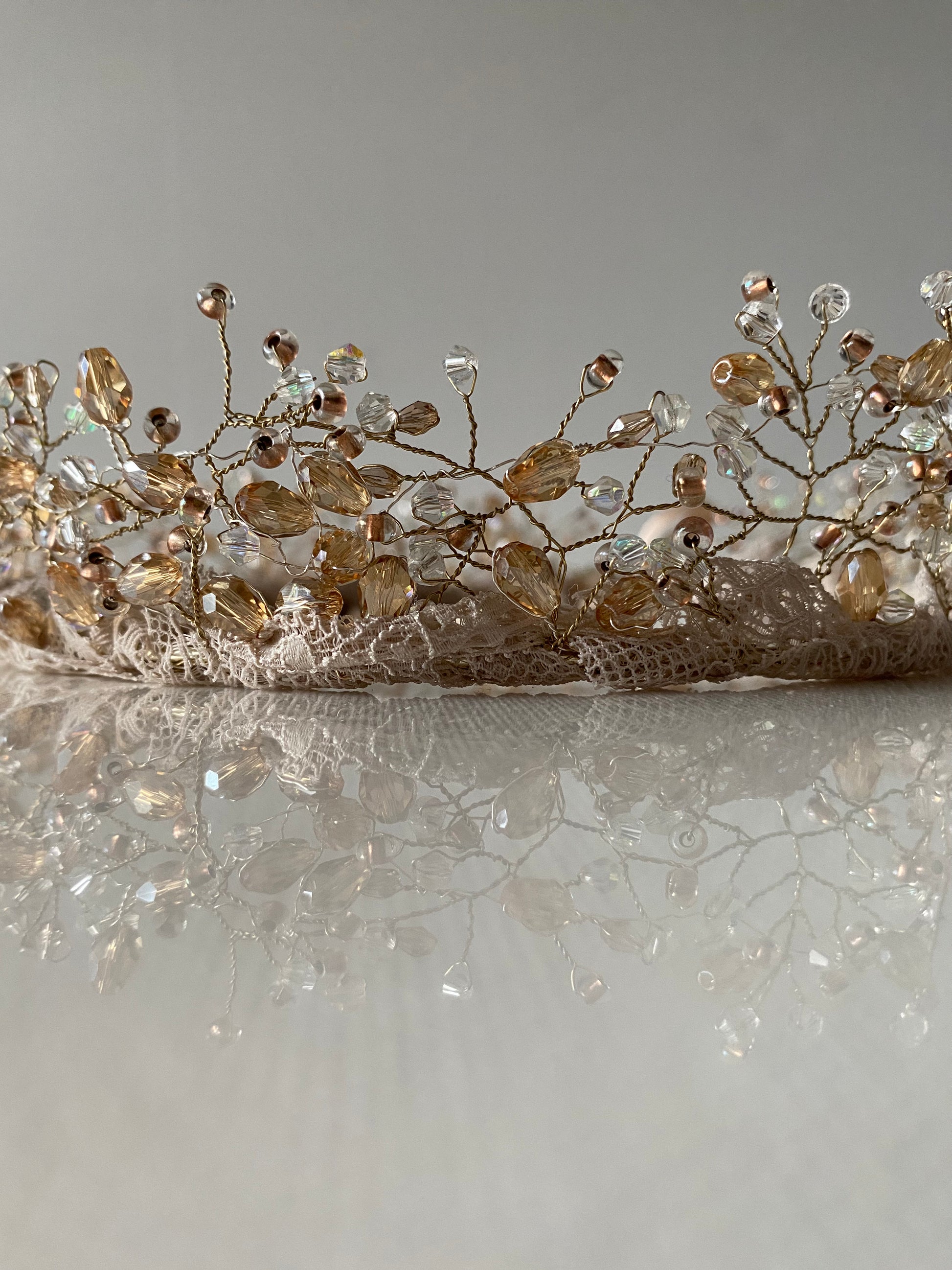 Stikla pērļu kronis baltos, bēšos un caurspīdīgos toņos ar mežģīnes apdares pamatni bēšā krāsā, sasienams