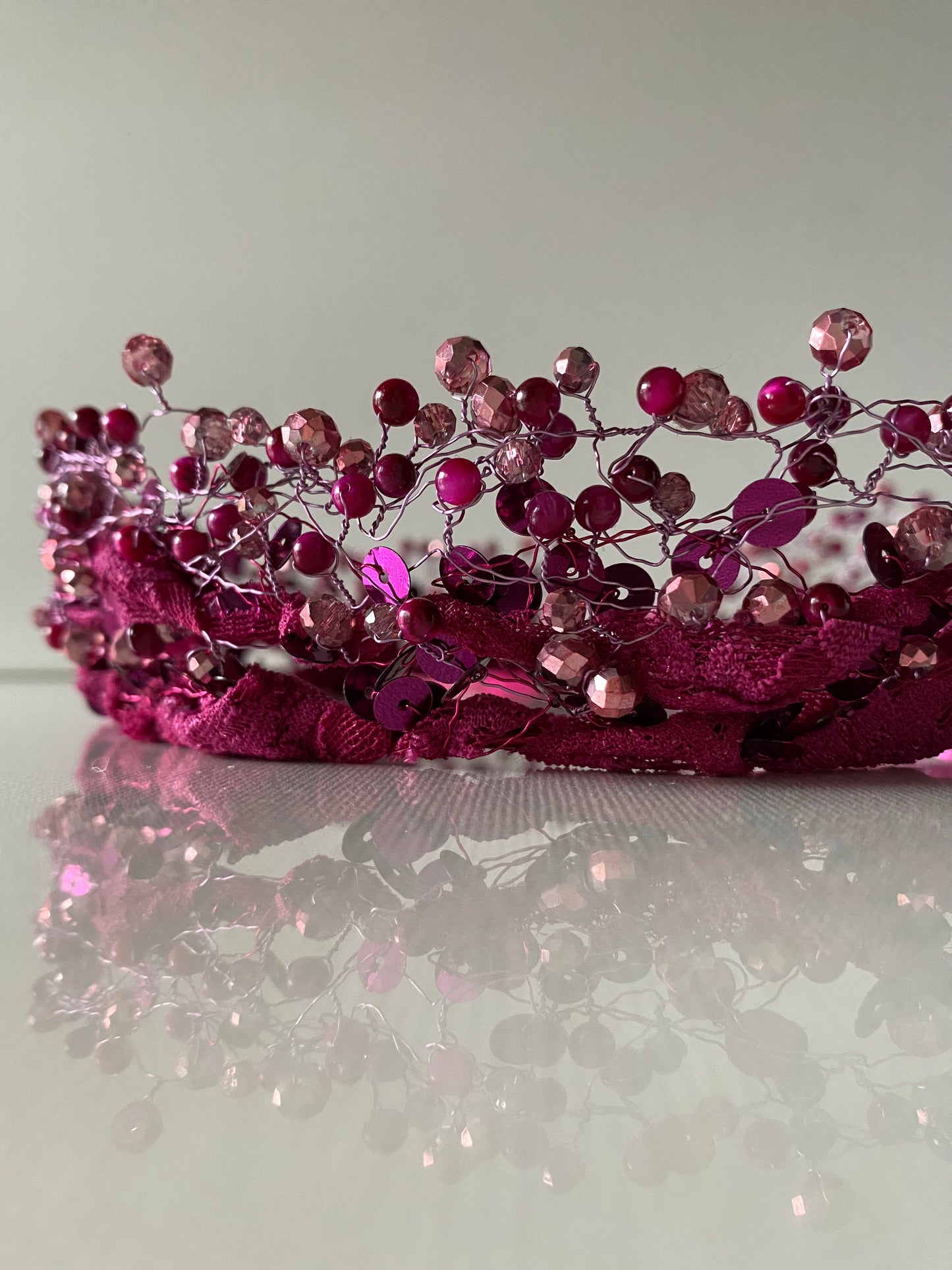 Stikla un akrila pērļu kronis tumšos un gaišos rozā toņos uz mežģīnes apdares pamatnes, sasienams