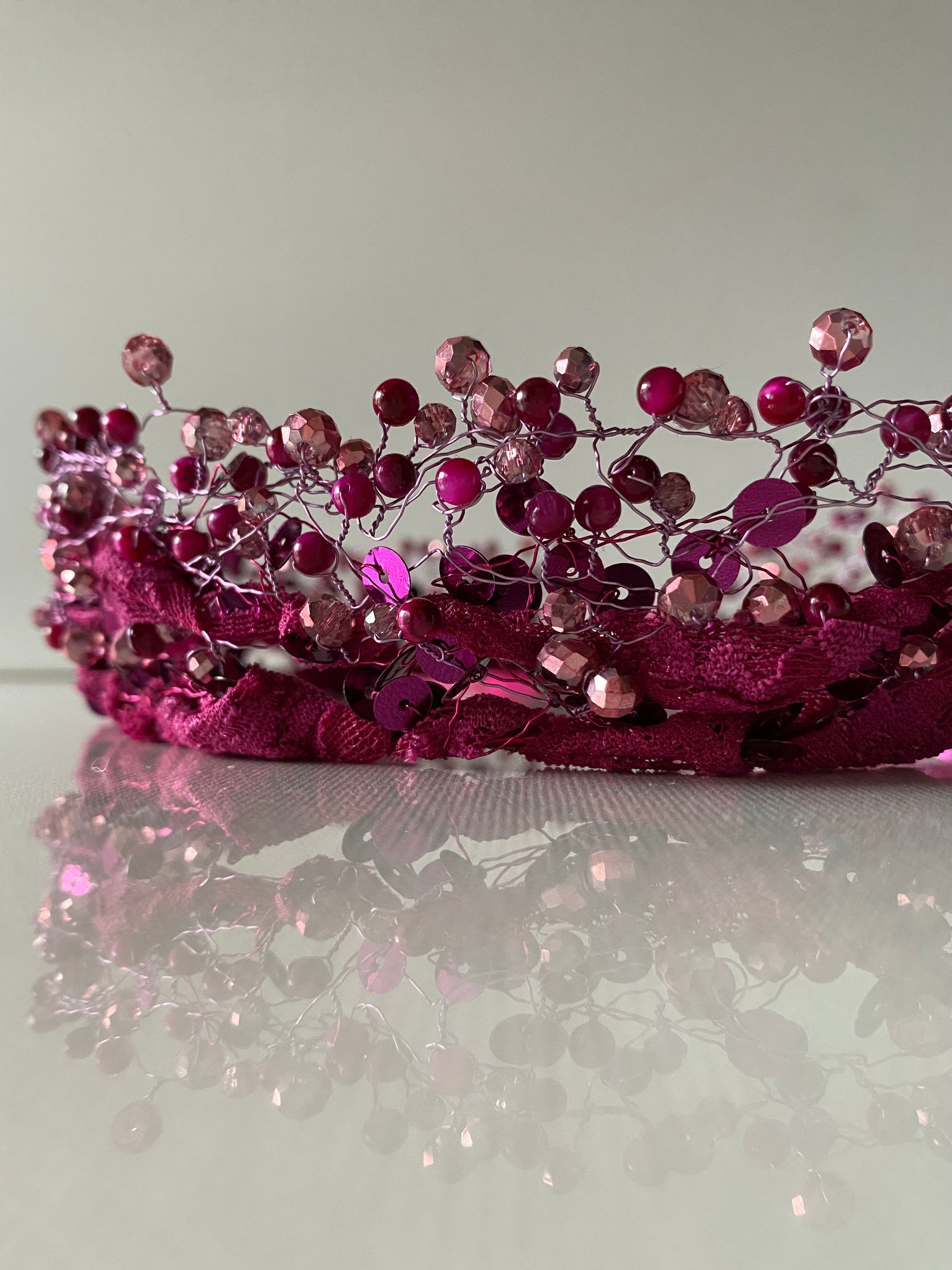 Stikla un akrila pērļu kronis tumšos un gaišos rozā toņos uz mežģīnes apdares pamatnes, sasienams