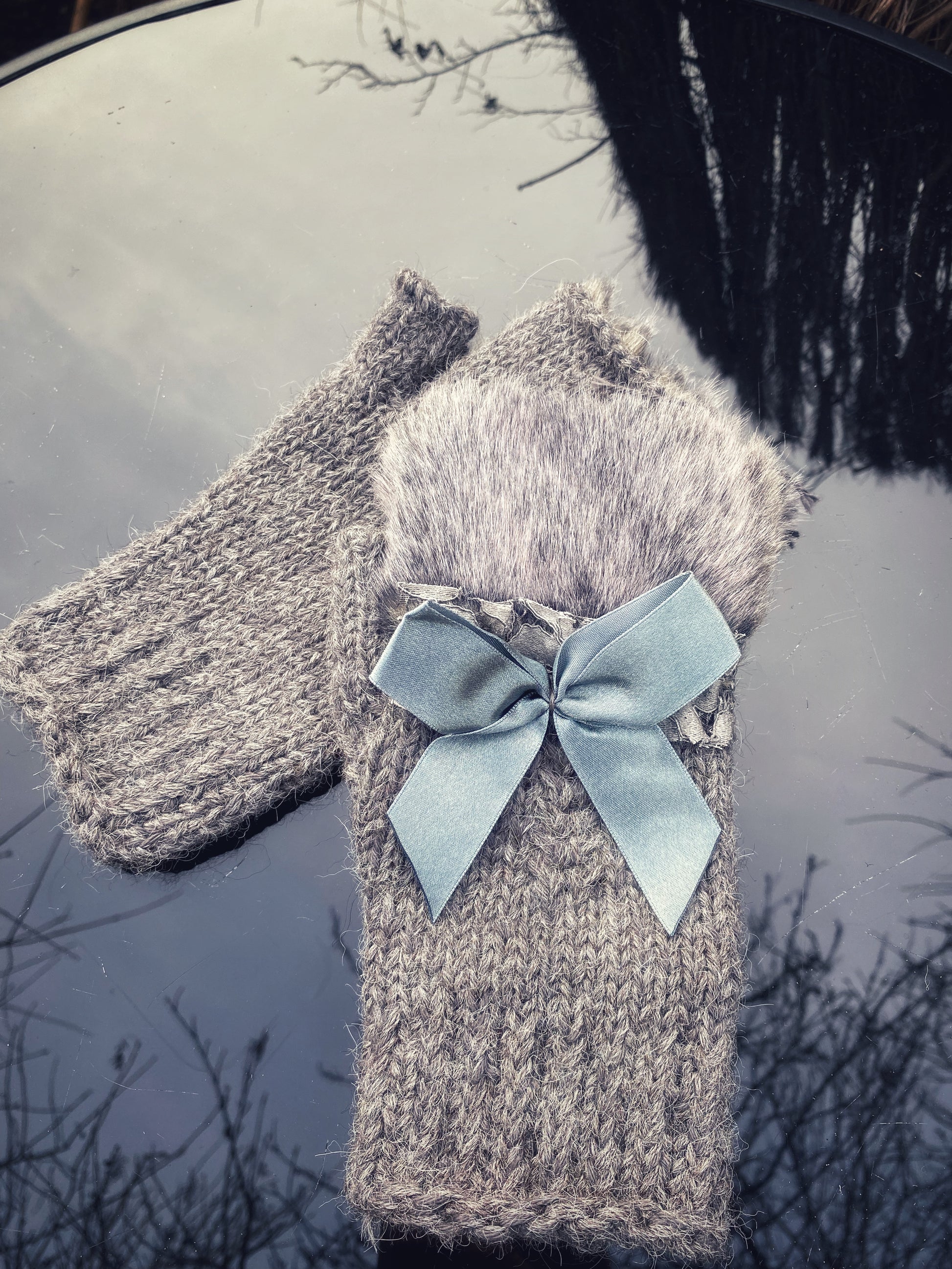 Pieaugušo puscimdiņi ar anatomisko īkšķi, no pelēkas alpakas dzijas ar mākslīgās kažokādas dekoru un atlasa banti